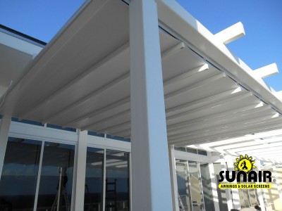 A white metal pergola awning in front of windows